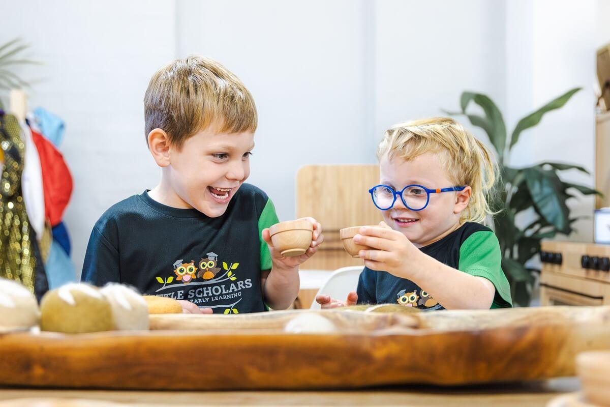 Toddlers engaging in social play and sensory learning with wooden toys at Little Scholars childcare centre.