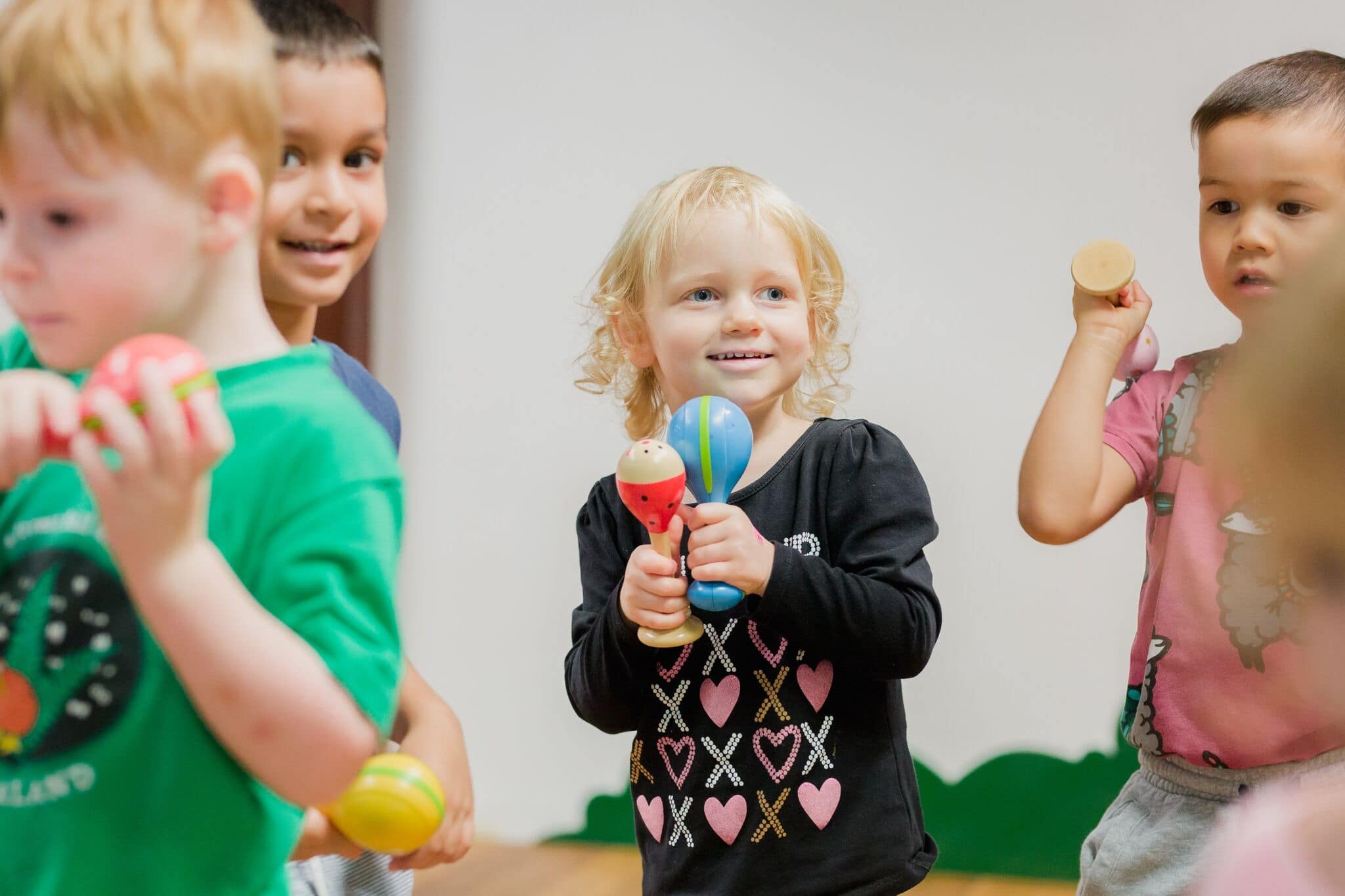 Children in a daycare classroom playing with colorful musical instruments, smiling and engaged in a group activity.