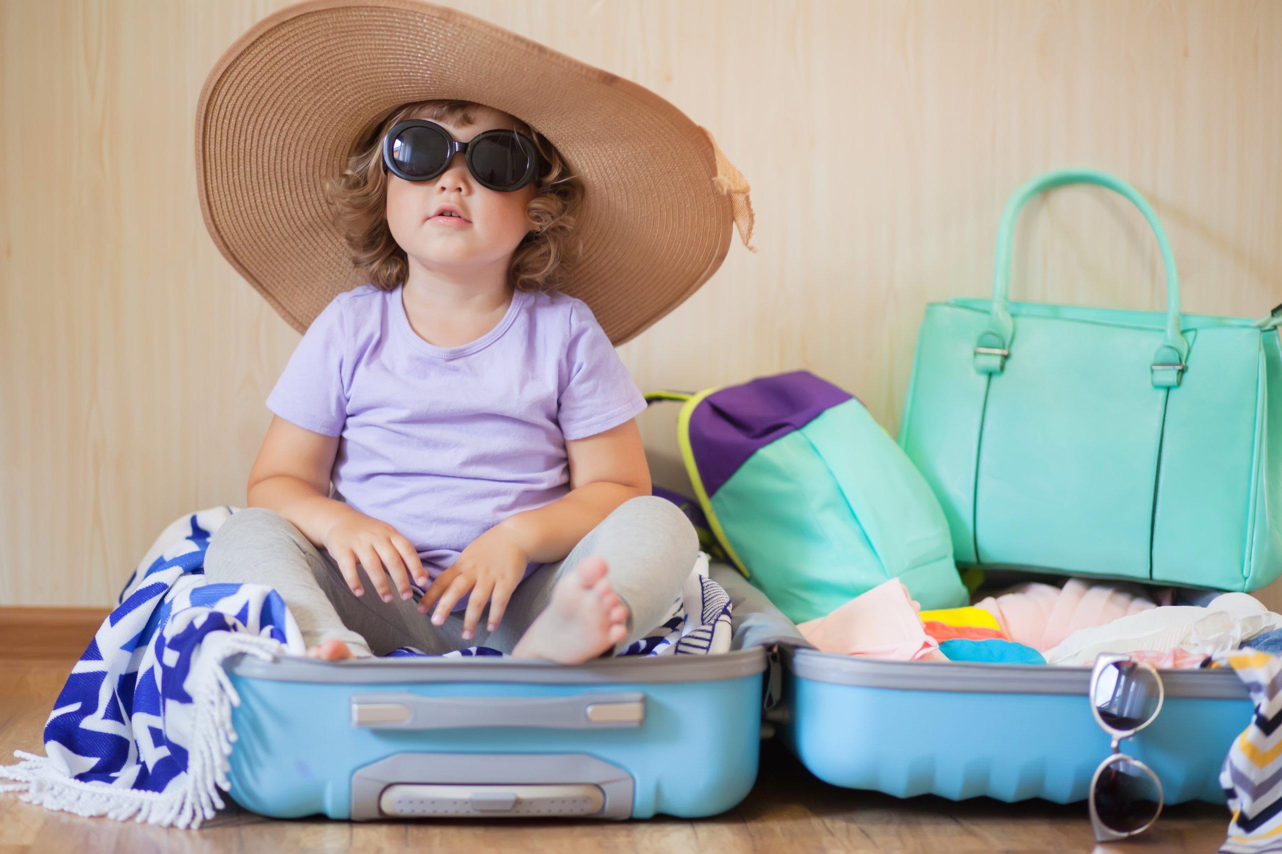 Adorable,toddler,girl,tourist,packs,clothes,into,a,large,suitcase