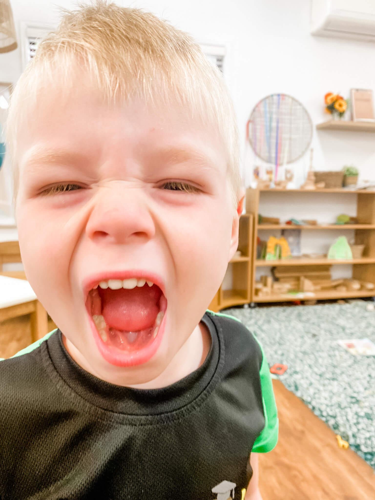 Little Scholars boy yelling with a wide open mouth, depicting strong emotion like anger or intense excitement in the classroom.